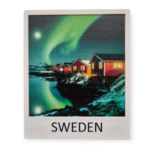Northern lights souvenir Sweden featuring red houses under a vibrant aurora borealis in a scenic landscape