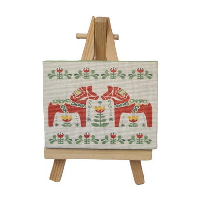 Swedish Dala horse decor featuring traditional red and green designs on a canvas with an easel